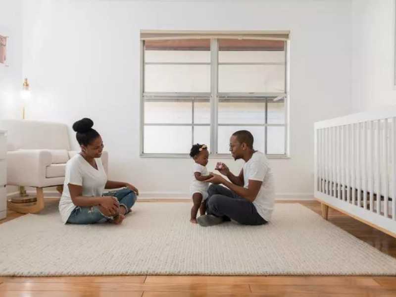Mother and father on floor with baby in a neutral colored room